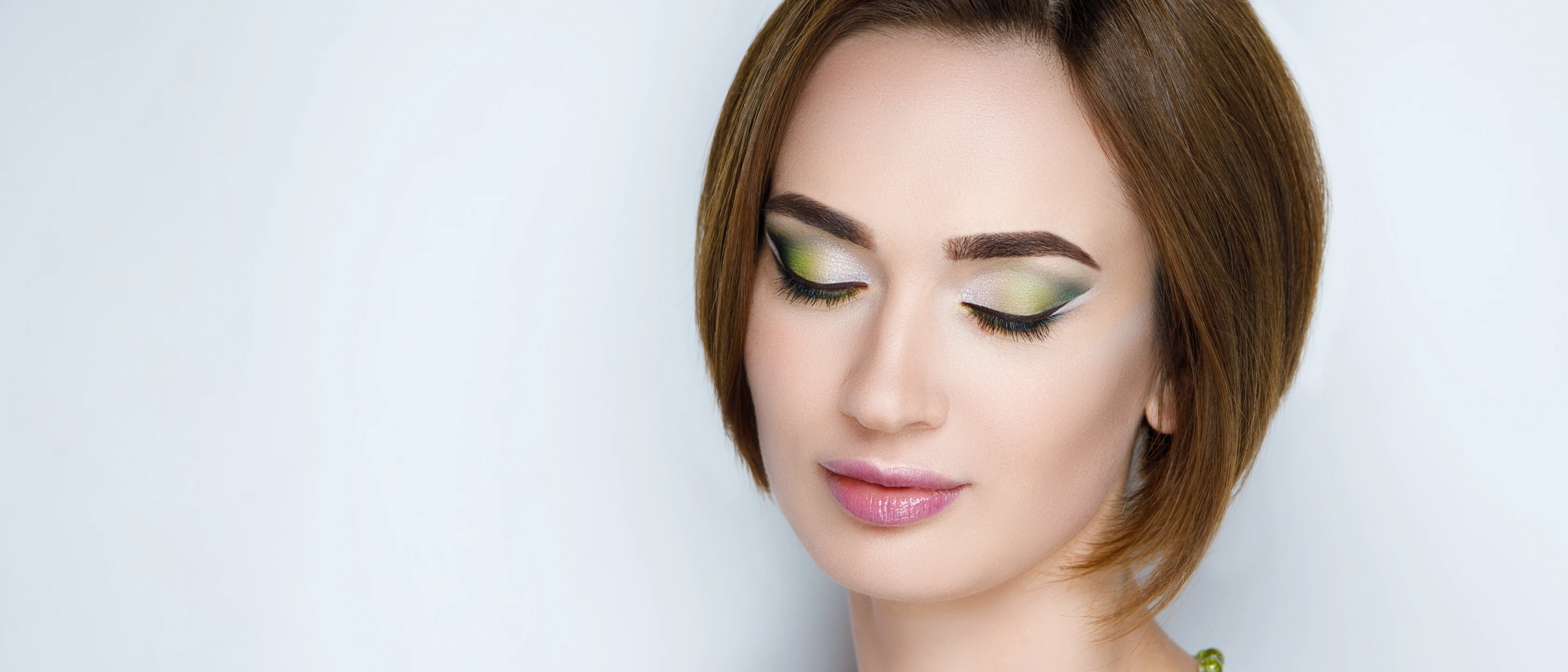 Close up of young woman's face with green and silver eyeshadow